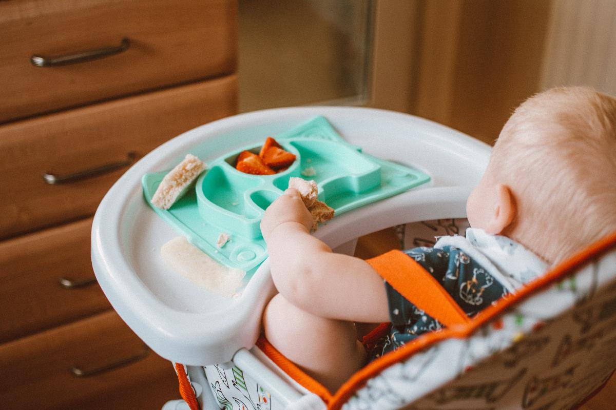 neonato che mangia su seggiolone